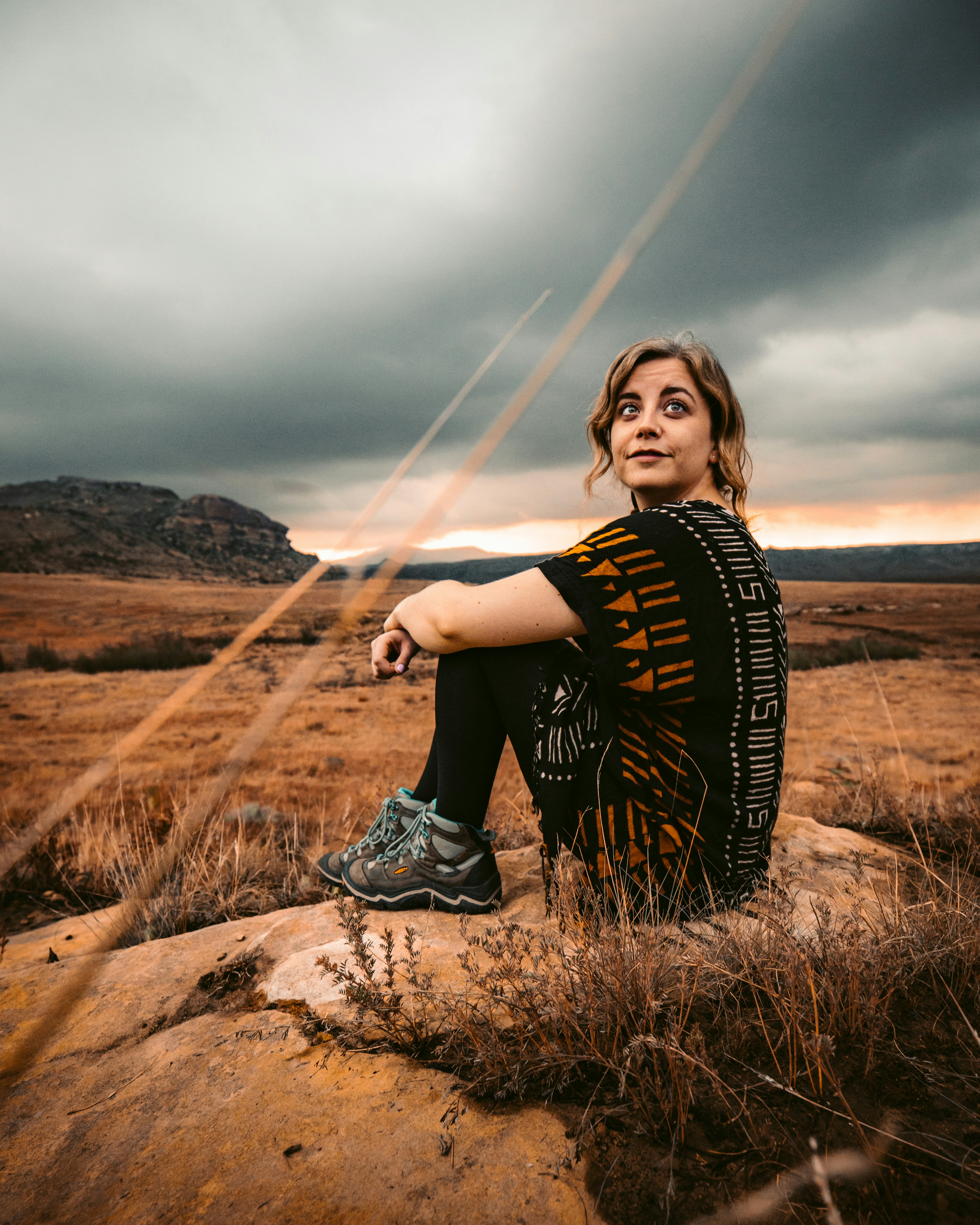 woman in black and white shirt sitting on brown rock during daytime